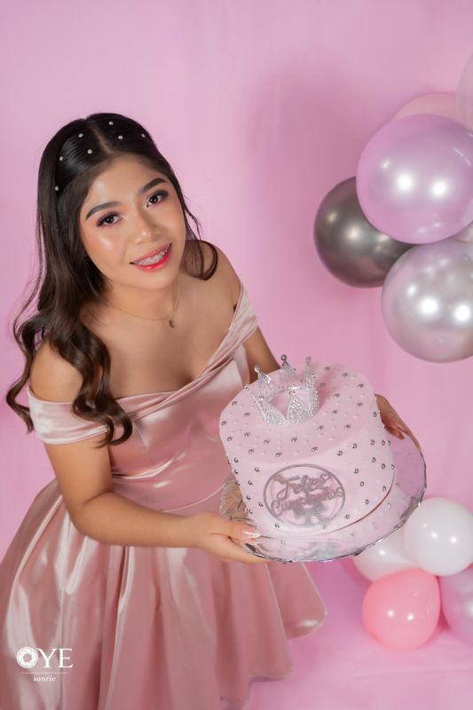 Quinceañera con vestido rosa y pastel en estudio