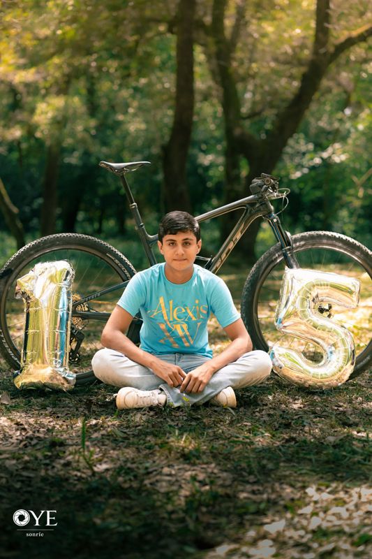 Quinceañero con su bicicleta y globos 1 y 5 en el bosque
